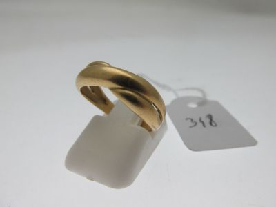 une image représentant une bague en or posée sur une surface blanche