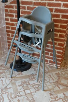 an image of a baby high chair in front of a brick wall