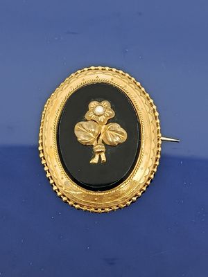 une image représentant une broche dorée et noire sur fond bleu