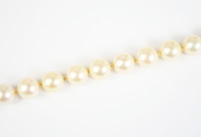 a close up of a pearl necklace on a white surface