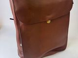 brown leather backpack on a white background with a red and blue ribbon
