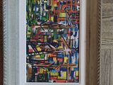 painting of a cityscape in a silver frame on a wooden wall