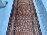 Un vieux tapis est posé par terre à côté d'une valise rouge.