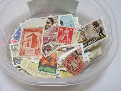 de nombreux timbres différents dans une boîte en plastique posée sur la table