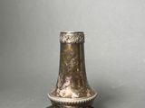 an antique silver plated candle holder on a grey background