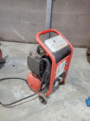 un petit compresseur d'air posé par terre dans un garage