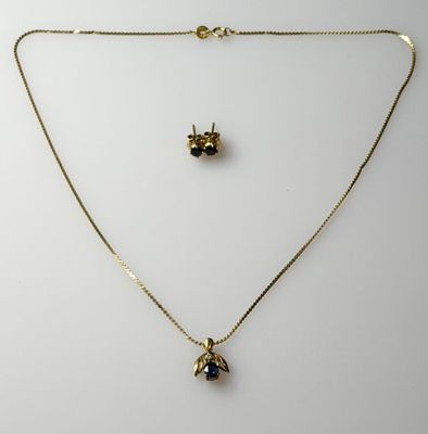 a gold necklace and earring set with a bee on it