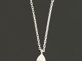 a small white diamond pendant hangs from a silver chain on a black background