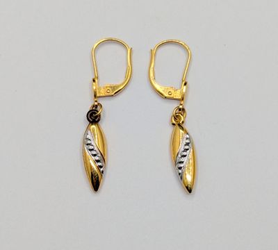 une paire de boucles d'oreilles en or et en argent sur fond blanc