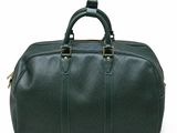 a green leather duffel bag sitting on top of a white surface