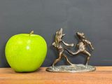 two figurines of a man and a woman fighting over an apple