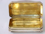 an image of a small silver box with a yellow glass inside