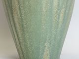 a green vase that is sitting on a white surface