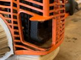 an orange and white chainsaw sitting on top of a wooden table