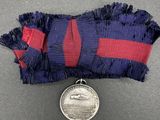 an old medal with a red and blue ribbon on a gray surface