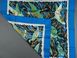 a close up of a blue scarf with birds on it