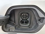 an electric car plugged in to a white car with a black handle