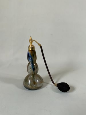 une petite bouteille en verre avec une poignée noire sur fond blanc