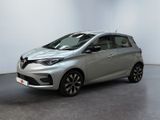 une voiture argentée garée dans une pièce blanche au sol noir