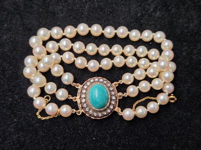 un gros plan sur un collier composé de perles et d'une pierre turquoise