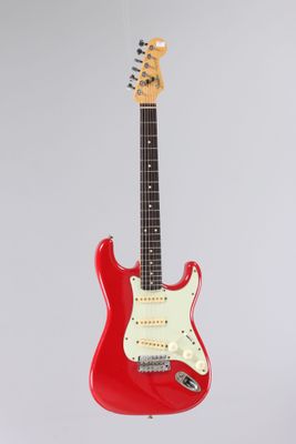 a red electric guitar hanging from a string on a white background