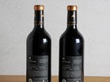 two bottles of wine sitting on top of a wooden table