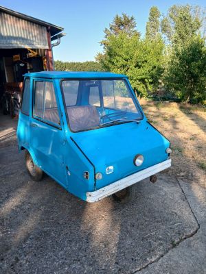 une petite voiture bleue garée devant un garage