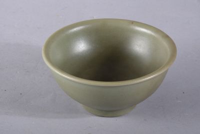 une petite tasse verte posée sur une surface blanche