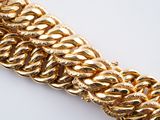 an image of a gold chain bracelet on a white surface