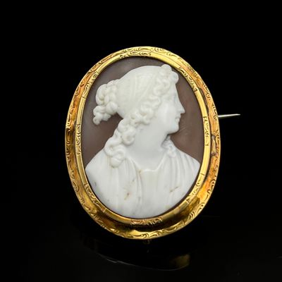 une image représentant le profil d'une femme sur une broche blanche et dorée
