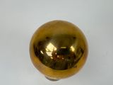 a shiny gold ball on a white surface