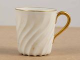 a close up of a white and gold coffee cup on a table