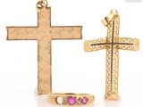 two gold crosses and a pink stone ring on a white surface