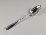 une cuillère en argent avec un manche de cuillère sur une surface blanche