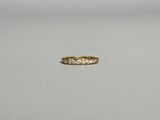 une bague en or jaune sertie de cinq diamants sur une surface blanche
