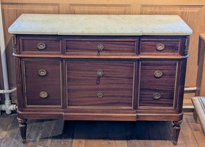 a wooden dresser with a marble top on a hard wood floor