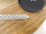 a silver watch sitting on a wooden table next to a charger
