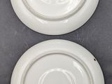 two white plates sitting on top of a table next to each other