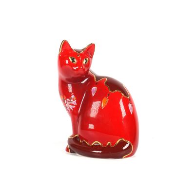 une figurine de chat rouge posée sur une surface blanche