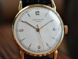 a close up of a gold wrist watch on a wooden table