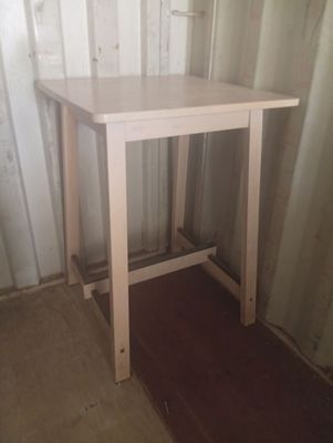 une table blanche avec un plateau en bois dans une pièce