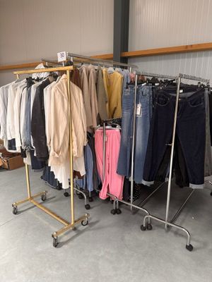 beaucoup de vêtements suspendus à une étagère dans une pièce