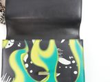 someone is holding a wallet with a green and yellow design on it