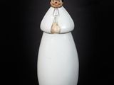 figurine en porcelaine représentant une femme vêtue d'une robe blanche et d'un chapeau, tenant un sac