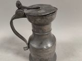 an old pewware pitcher with a handle on a white surface
