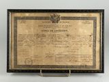 un ancien certificat est exposé dans un cadre en bois