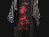 a black coat with red flowers is hanging on a hanger