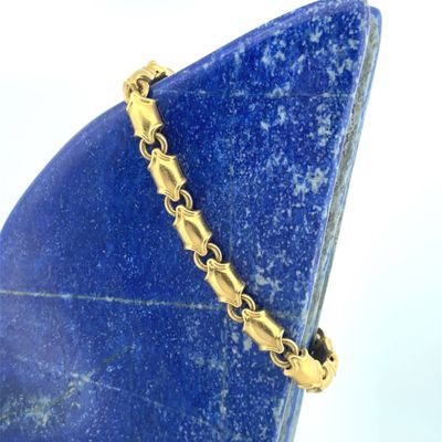 gold plated bracelet on a blue stone stand with a white background