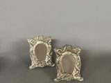 two silver picture frames with a mirror on top of a table