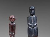 two wooden statues of a man and a woman standing next to each other